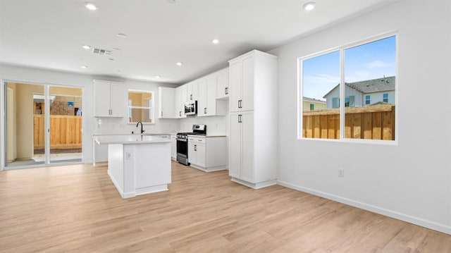 4040 Molten Creek Way, Roseville, CA 95747 - kitchen featuring stainless steel appliances, light countertops, white cabinets, a kitchen island, and light wood-style flooring