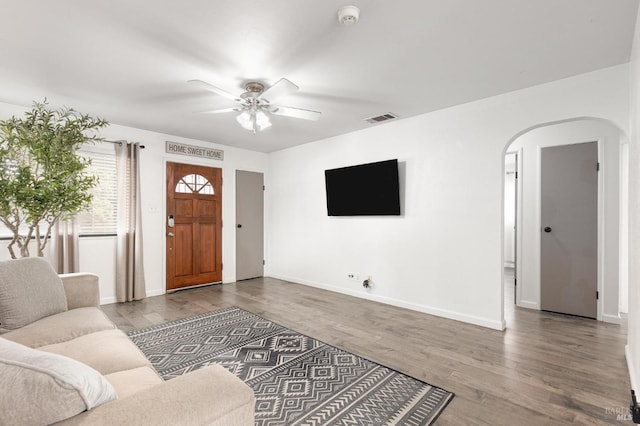 living room featuring arched walkways, visible vents, ceiling fan, and wood finished floors