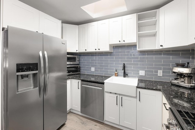 kitchen with a sink, decorative backsplash, appliances with stainless steel finishes, white cabinetry, and open shelves