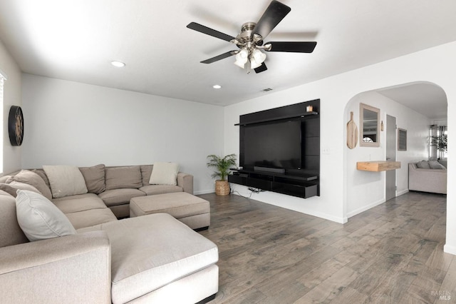 living area featuring a ceiling fan, wood finished floors, baseboards, and arched walkways