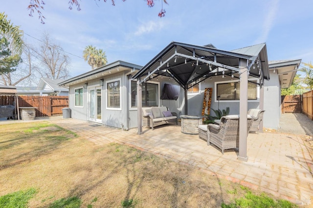 rear view of property featuring a gazebo, an outdoor living space, a patio, and a fenced backyard