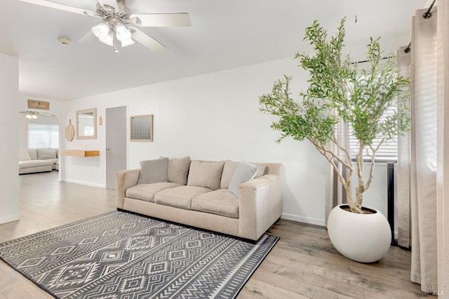 living area featuring a ceiling fan, wood finished floors, and baseboards