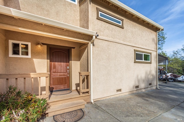 property entrance with stucco siding and crawl space