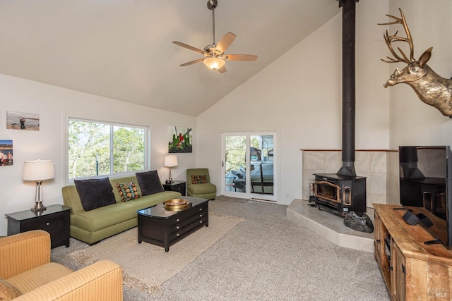 carpeted living room featuring a wealth of natural light, a ceiling fan, high vaulted ceiling, and a wood stove