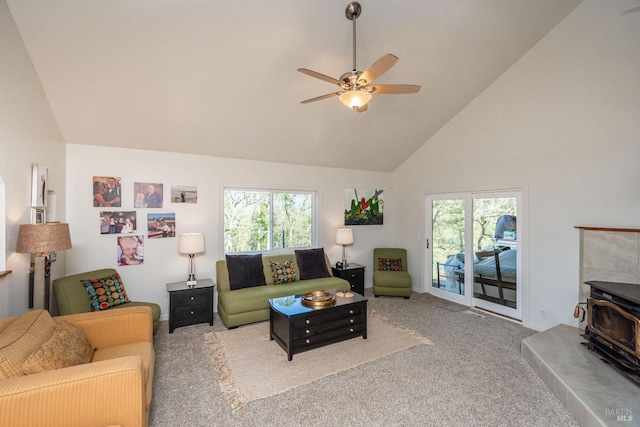 carpeted living area featuring a wood stove, plenty of natural light, a ceiling fan, and high vaulted ceiling