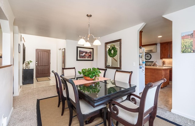 dining room featuring light tile patterned flooring, light colored carpet, baseboards, and an inviting chandelier