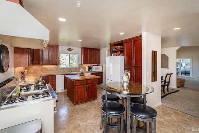 kitchen with tasteful backsplash, a center island, premium range hood, light countertops, and white appliances