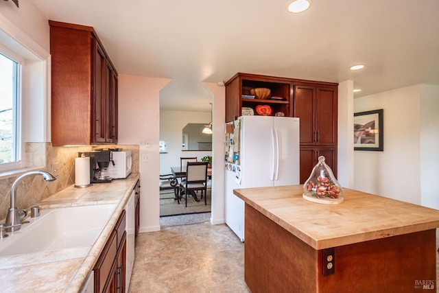 kitchen with white appliances, butcher block counters, a sink, decorative backsplash, and a center island