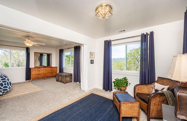 sitting room featuring visible vents, ceiling fan, and carpet flooring