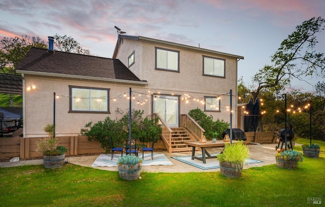 back of house with stucco siding, a lawn, and a patio area