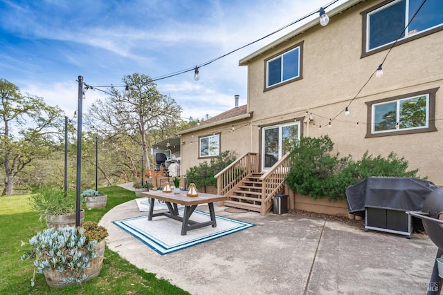 rear view of property with stucco siding, a lawn, and a patio