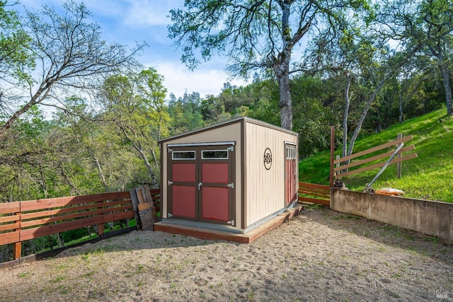 view of shed featuring a fenced backyard and a view of trees