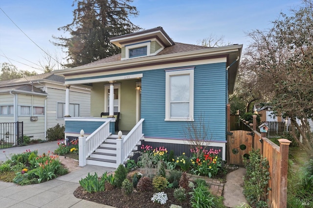 bungalow-style house with covered porch and fence