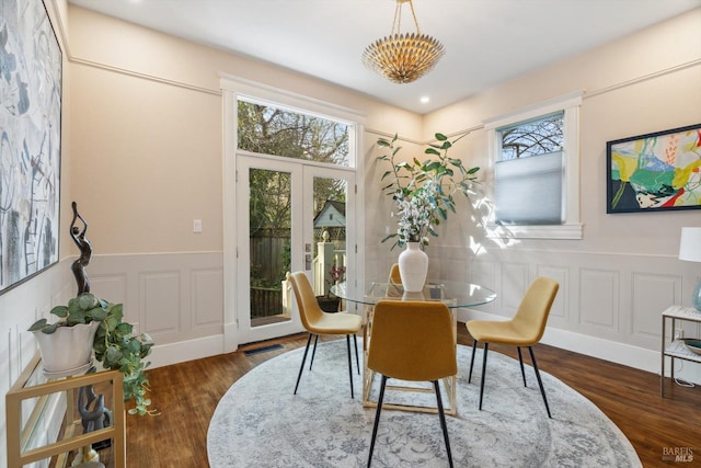 dining room featuring visible vents, wood finished floors, wainscoting, and a decorative wall