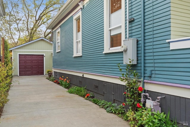 view of home's exterior with crawl space, a detached garage, an outbuilding, and concrete driveway