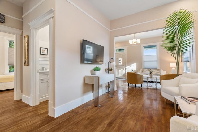 living area featuring baseboards, a notable chandelier, and dark wood-style flooring