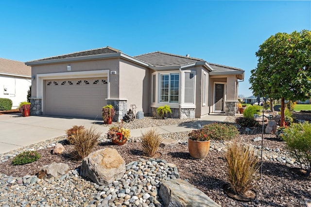 view of front of home featuring a tiled roof, stucco siding, a garage, stone siding, and driveway