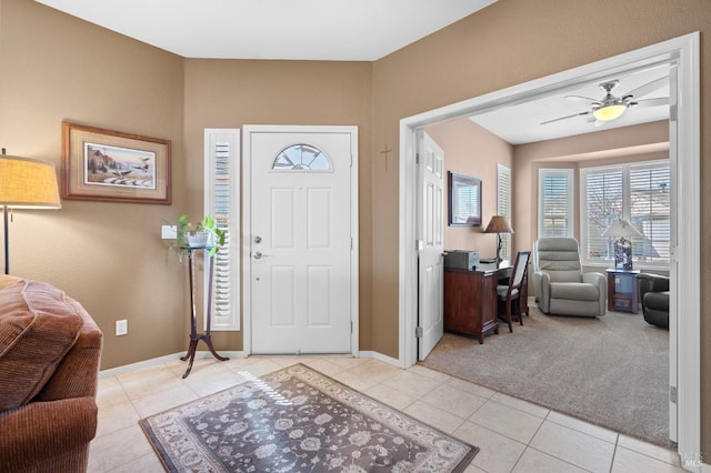 entrance foyer with light tile patterned floors, light colored carpet, baseboards, and ceiling fan