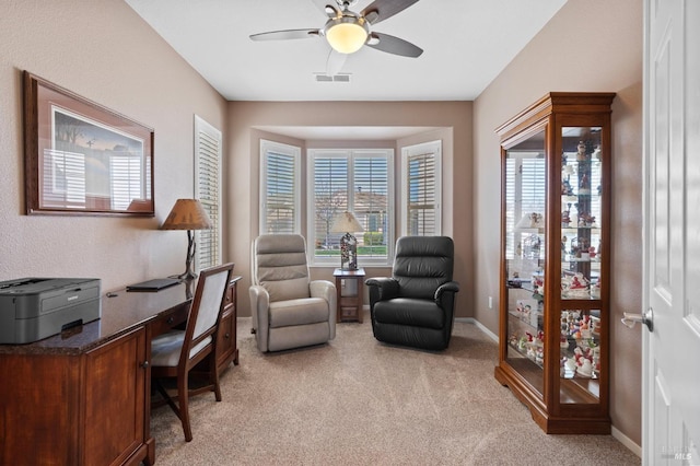 office space featuring a ceiling fan, light colored carpet, visible vents, and baseboards