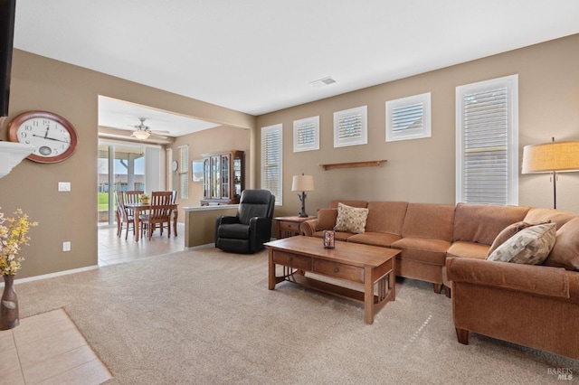 living area with visible vents, baseboards, light carpet, light tile patterned floors, and a ceiling fan