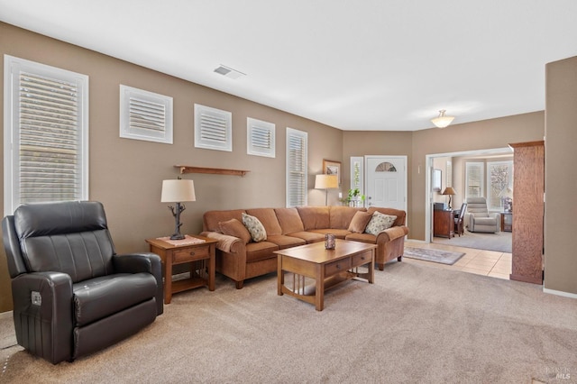 living area with light tile patterned floors, visible vents, and light colored carpet