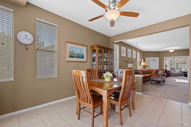 dining space featuring light carpet, light tile patterned floors, baseboards, and ceiling fan