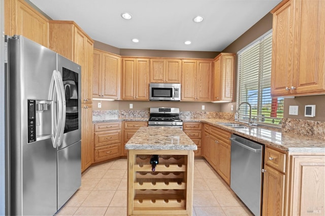 kitchen featuring light tile patterned floors, light brown cabinets, appliances with stainless steel finishes, and a sink