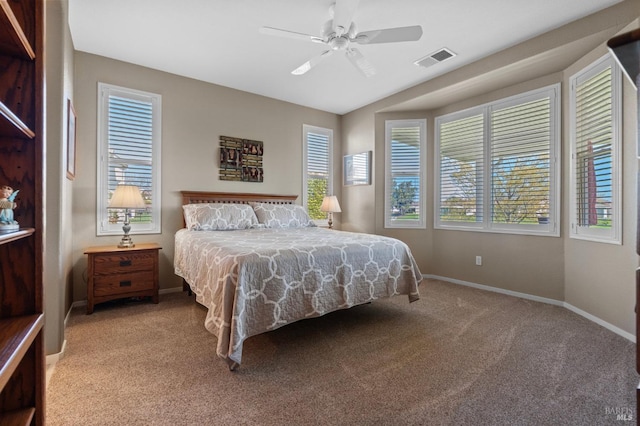 carpeted bedroom featuring a ceiling fan, multiple windows, baseboards, and visible vents