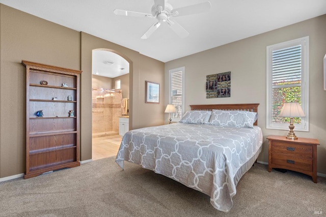 bedroom with carpet, baseboards, arched walkways, ceiling fan, and ensuite bathroom