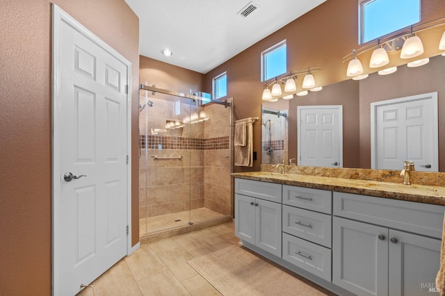 bathroom featuring double vanity, a stall shower, visible vents, and a sink