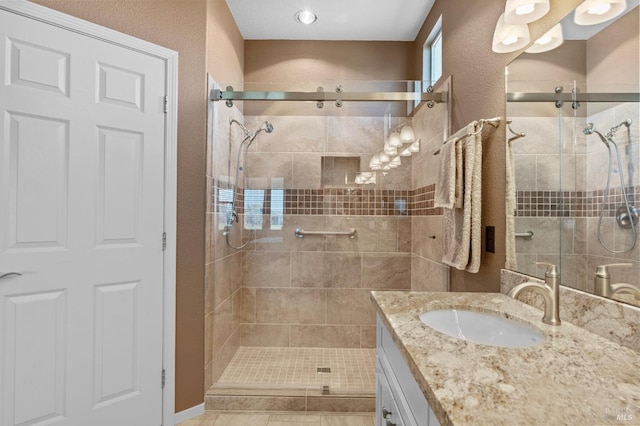 bathroom with a stall shower, vanity, and a textured wall