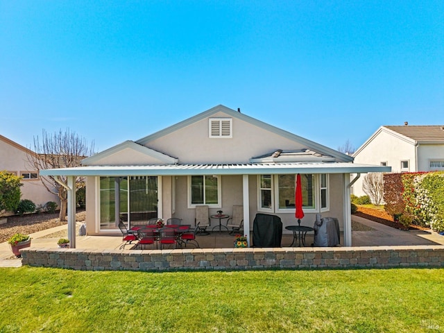 rear view of house featuring a yard, a patio area, and stucco siding