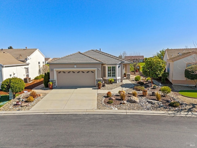 view of front of property with stucco siding, a tile roof, concrete driveway, a garage, and central AC unit