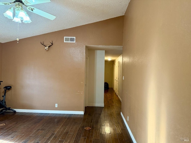 spare room featuring wood finished floors, baseboards, visible vents, lofted ceiling, and ceiling fan