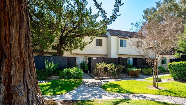view of front facade with fence private yard, stucco siding, and a front yard