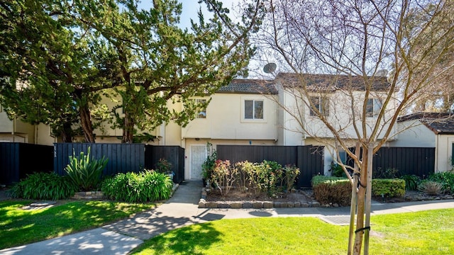 multi unit property featuring stucco siding, a fenced front yard, and a front lawn