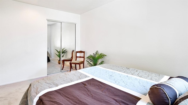 carpeted bedroom featuring baseboards and a closet