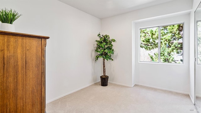 spare room with light colored carpet and baseboards