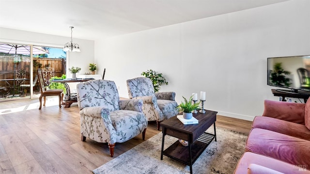 living area with baseboards, wood finished floors, and a chandelier