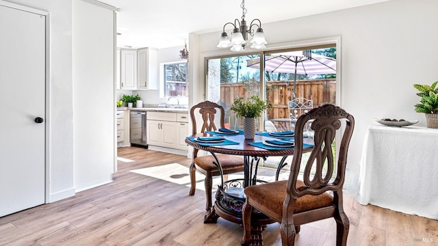 dining room with an inviting chandelier, baseboards, and light wood-type flooring