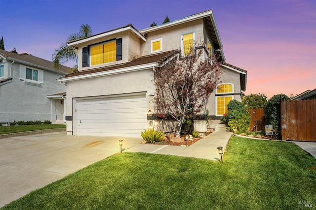 traditional-style house with stucco siding, a garage, driveway, and fence