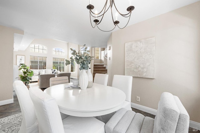 dining area featuring stairs, stone finish floor, a notable chandelier, and baseboards