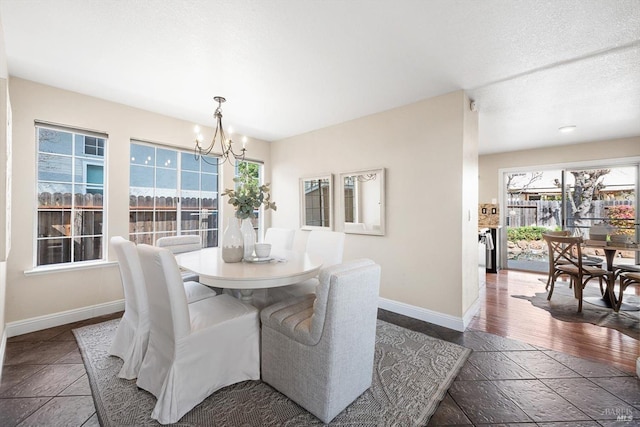 dining space featuring an inviting chandelier, a textured ceiling, and baseboards