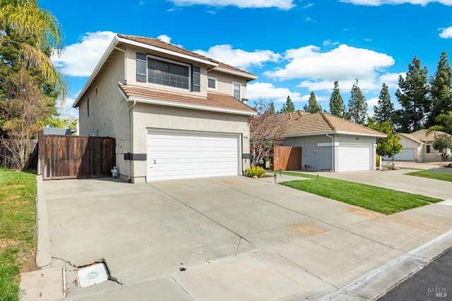 traditional home with a tiled roof, a garage, fence, and stucco siding