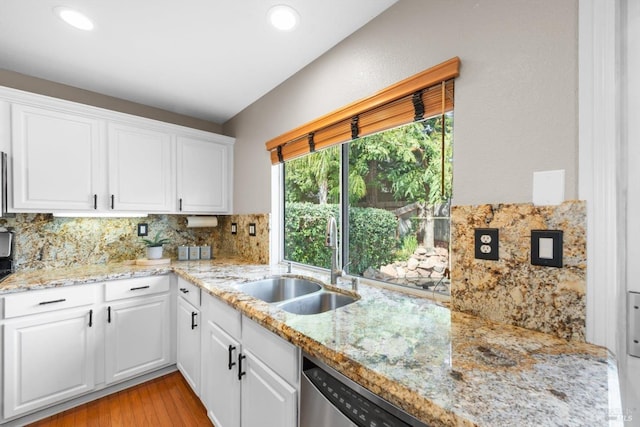 kitchen featuring decorative backsplash, white cabinets, dishwasher, and a sink