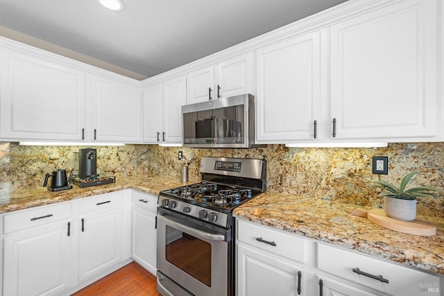 kitchen with white cabinetry, backsplash, and appliances with stainless steel finishes