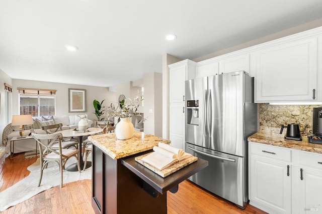 kitchen with decorative backsplash, light wood-style floors, white cabinets, and stainless steel fridge with ice dispenser