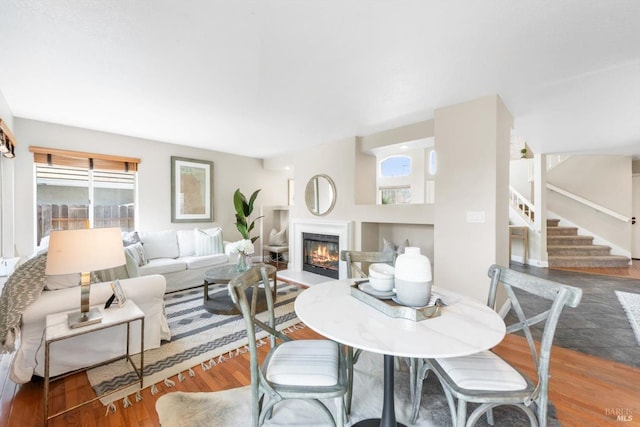 dining space featuring stairway, a glass covered fireplace, and wood finished floors