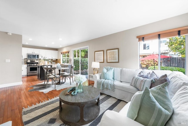 living area with recessed lighting, light wood-type flooring, and baseboards