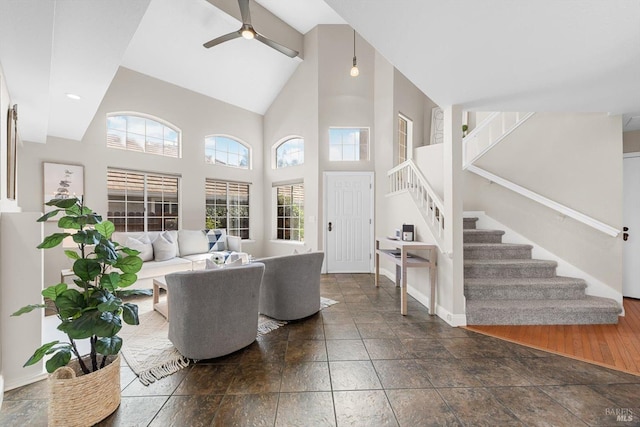 living room with stairs, plenty of natural light, ceiling fan, and high vaulted ceiling